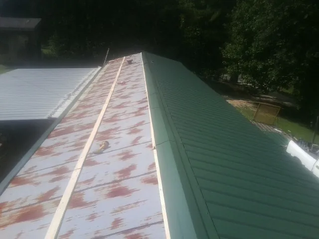 Old rusted panels beside newly installed green metal roofing — Wind Damage Roof Repair by Roofing Brothers in Edgefield