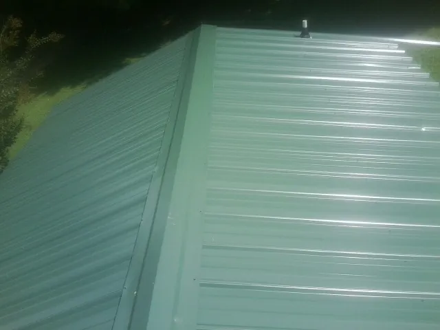 New green metal panels meeting at the ridge of a roof — Flat Roof Repair work by our crew in Edgefield