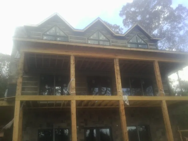 Dormers and porch framing on a large log home under construction — Roof Coating work by our crew in Edgefield