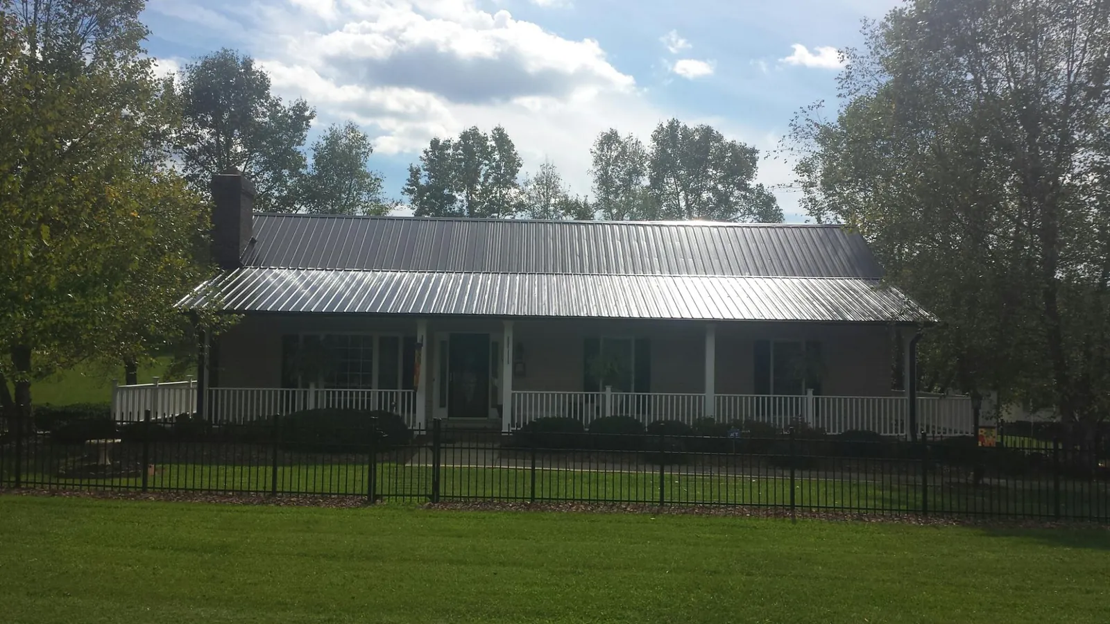 Gray metal roof on a brick ranch with a full width front porch — Gutter Guard Installation work by our crew in Edgefield