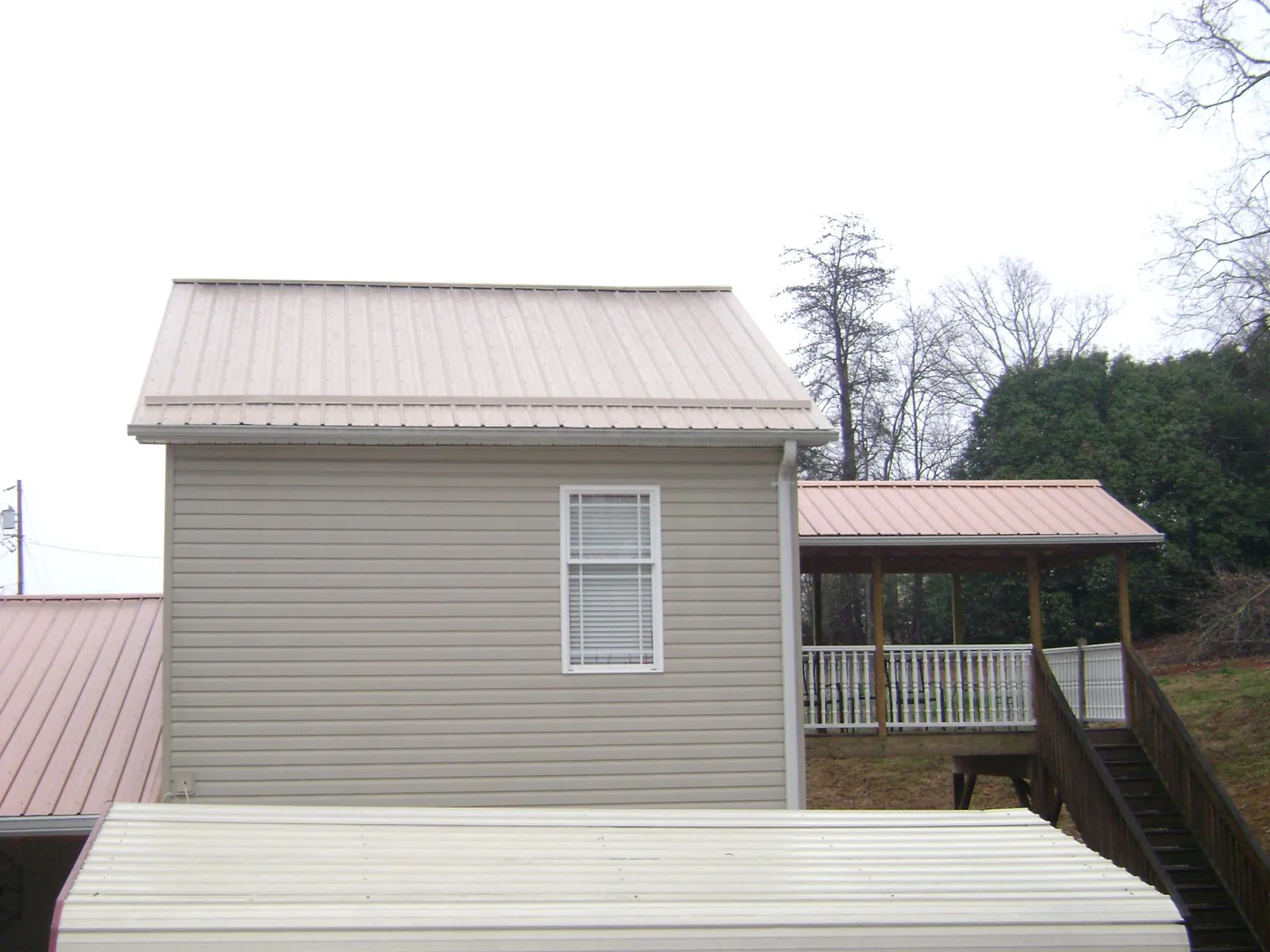 Tan metal roofs on a two story addition and attached porch, from a Roof Replacement job in Edgefield
